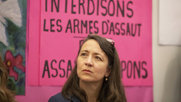 Gros plan de Nathalie Provost devant une pancarte sur laquelle on peut lire : «Interdisons les armes d'assaut».