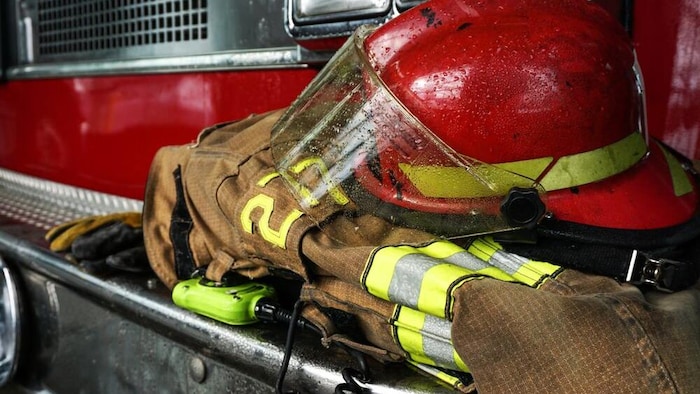 Un casque de pompier et un uniforme de pompier sur le côté d'un camion de pompier. 