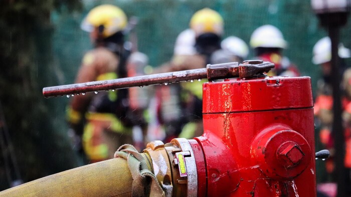 Une borne-fontaine avec des pompiers.