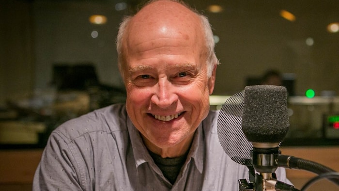 Jean-Marie De Koninck dans un studio de radio. Il regarde la caméra en souriant.