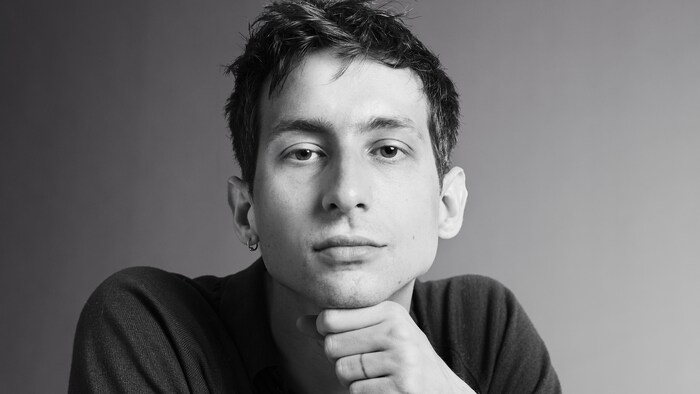 Photo en noir et blanc de Gabriel Cholette qui tient son menton avec sa main.