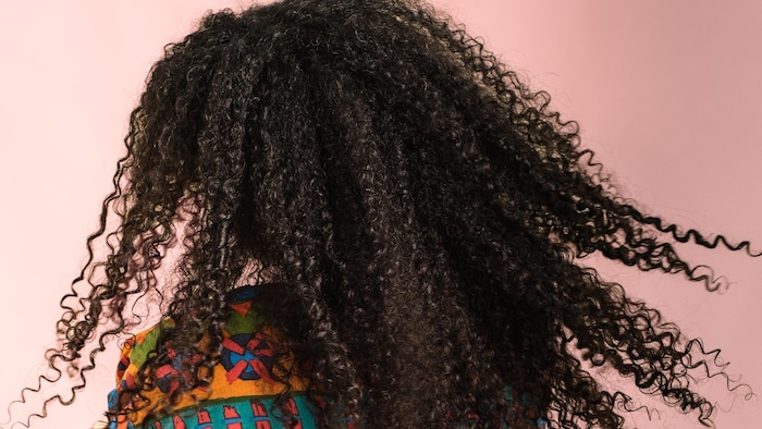 La femme aux cheveux bouclés est photographiée de dos.