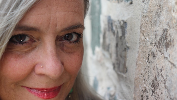 Caroline Moffet regarde l'objectif, accotée sur un mur.