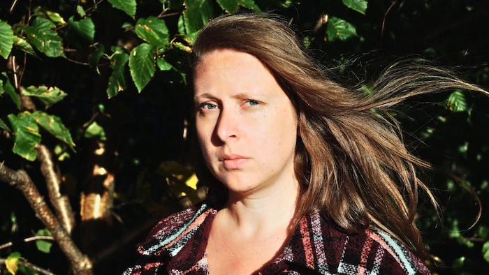 L'autrice prend la pose en extérieur, les cheveux au vent.