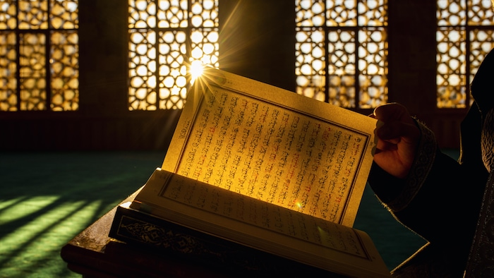 Une personne lit un livre écrit en arabe.
