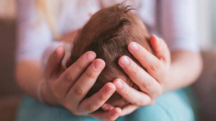 Une mère tient son nouveau-né dans ses mains.