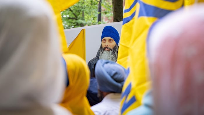 Des manifestants tiennent des drapeaux du mouvement Khalistan et une pancarte qui porte une image du visage de Hardeep Singh Nijjar.