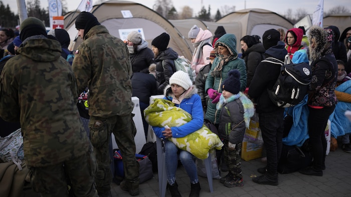 Des femmes et des enfants visiblement fatigués attendent à un poste-frontière en Pologne.