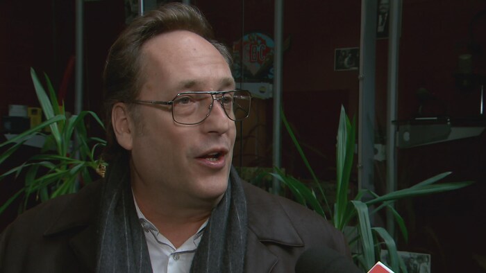 Un homme parle avec en arrière-plan des plantes vertes.