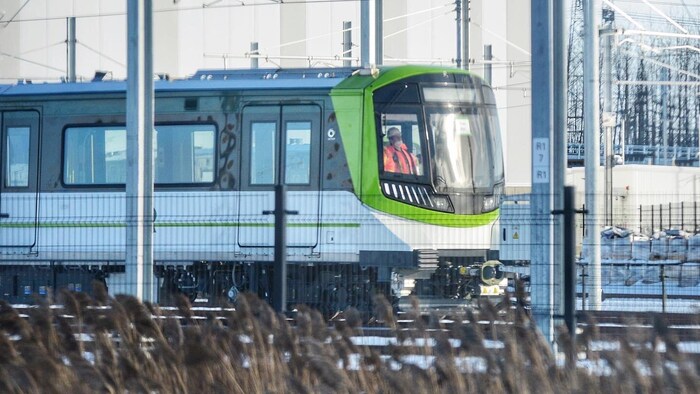 Un train du REM circule sur une voie, sous des fils électriques, à Brossard.
