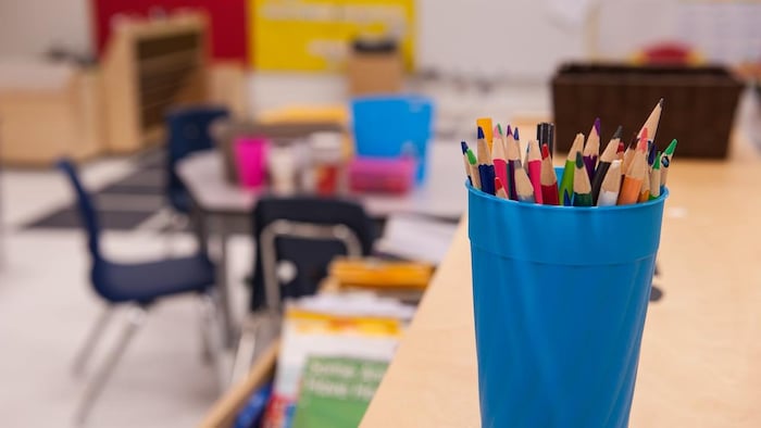 Une classe vide; des crayons en avant-plan.