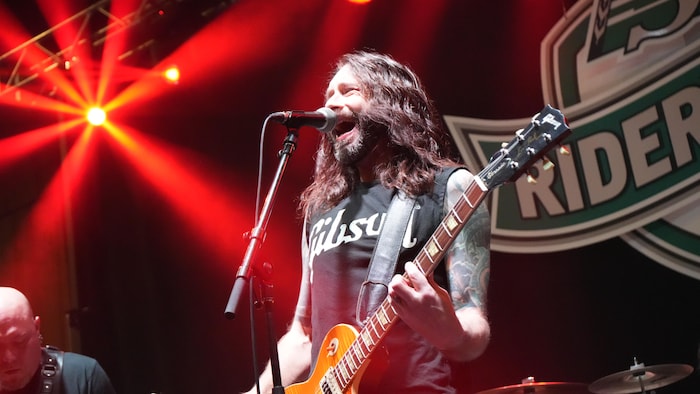 Un homme sur scène joue de la guitare électrique.