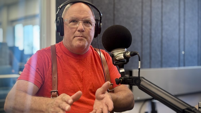 Un homme devant un micro dans un studio de radio.