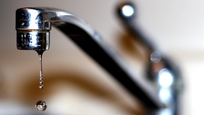 Un filet d'eau coule d'un robinet dans une cuisine.
