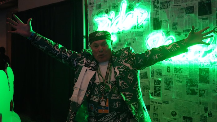 Un homme pose pour une photo, les bras tendus, afin de montrer son soutien aux Roughriders de la Saskatchewan.