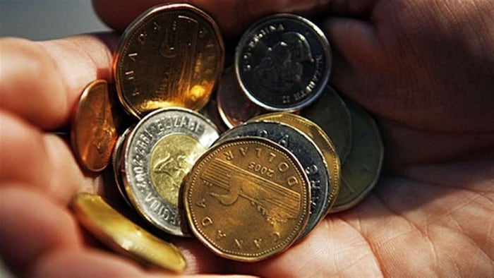 Un homme tient dans sa main des pièces de monnaie.