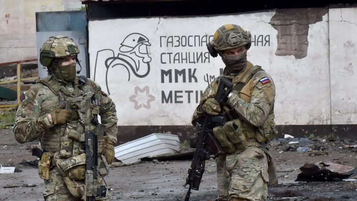 Des militaires russes montent la garde devant la partie détruite de l'usine sidérurgique Ilyich dans la ville portuaire de Marioupol, en Ukraine, le 18 mai 2022.