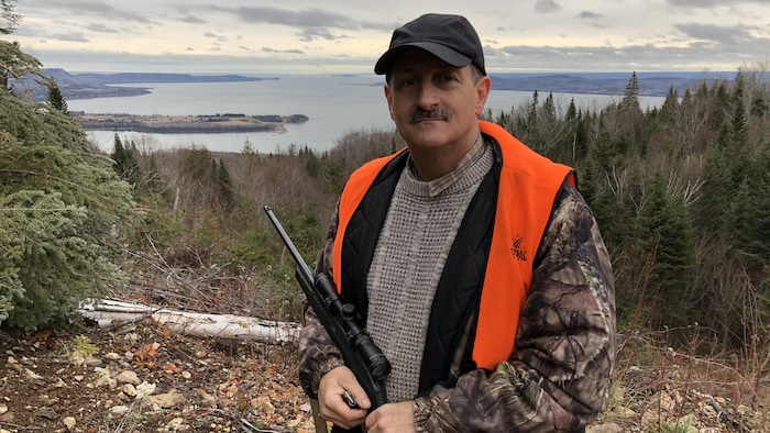 Le député Sylvain Roy prend la pose en habit de chasseur, avec en arrière plan la baie d'Escuminac