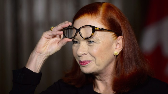 Catherine Tait soulève ses lunettes pour répondre à un journaliste.