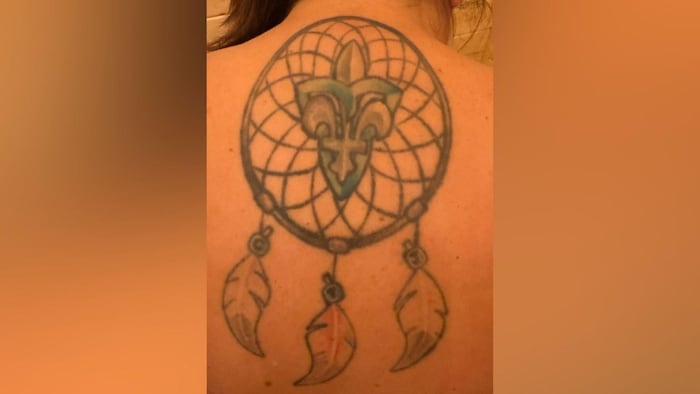 Tatouage d'une fleur de lys et d'un trille dans un capteur de rêves.