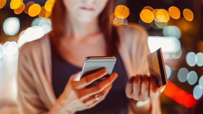 Une femme tient son téléphone cellulaire.