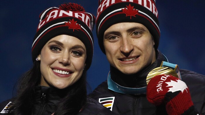 Les patineurs souriants sur le podium posent fièrement avec leurs médailles d'or autour du cou.