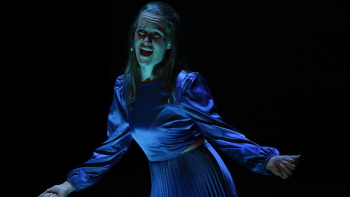 Stéphanie Morin-Robert debout sur scène en spectacle les bras ouverts présentant son spectacle « Blindside ».
