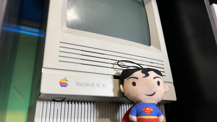 Un toutou de Superman devant le premier ordinateur Macintosh.