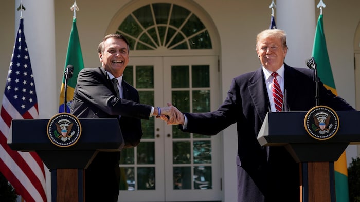 Tout sourire, Jair Bolsonaro et Donald Trump se serrent la main devant la Maison-Blanche.
