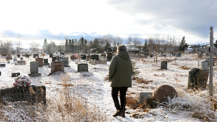 Une femme marche dans un cimetière.