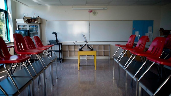 Une classe vide, les chaises levées sur les bureaux.