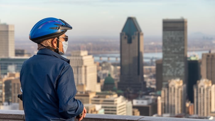 Sur le belvédère du mont Royal, un homme qui porte un casque de vélo et un masque regarde à l'horizon.