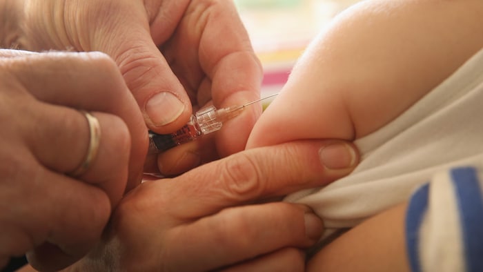 Gros plan sur le bras d'un bébé vacciné par un pédiatre.