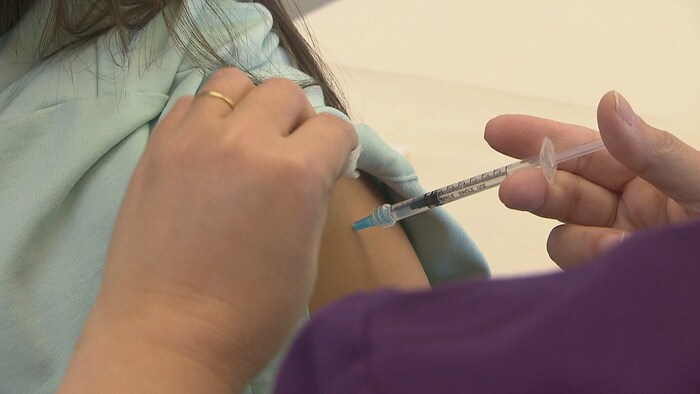 Une infirmière administre une dose de vaccin à une personne. 