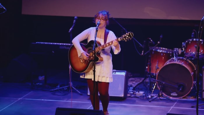Valérie Bouchard jouant seule sur scène avec sa guitare.