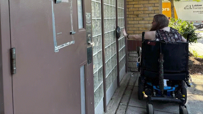 Une femme en fauteuil roulant tente d'appuyer sur un bouton d'accessibilité.