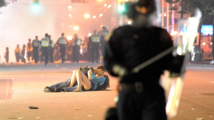 Un couple s'embrasse sur le sol en pleine émeute.
