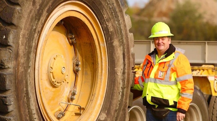 Harold Michaud pose devant une géante roue de camion.