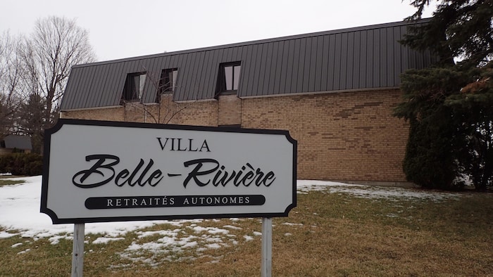 Un panneau sur lequel il est écrit Villa Belle-Rivière retraités autonomes, devant un immeuble.