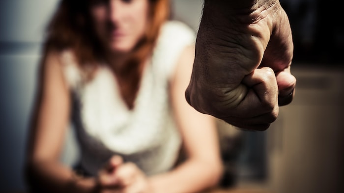Un hombre con el puño amenazante frente a una mujer.