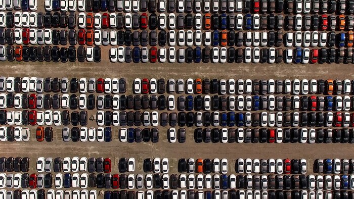 Vue aérienne d'un stationnement de voitures neuves.