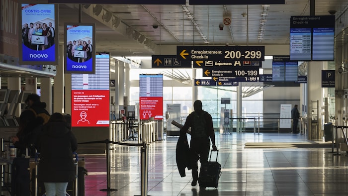 Un homme marche dans l'aéroport de Montréal.