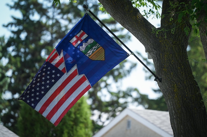 Un drapeau combinant les couleurs de l'Alberta et des États-Unis flotte au vent dans la cour arrière d'une maison à Edmonton, le 15 juin 2025.
