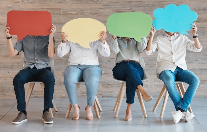 Des personnes assises sur des chaises tiennent des pancartes en forme de bulles de bd pour conceptualiser le principe de conversation.