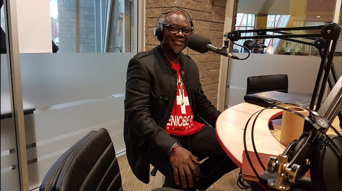 Un homme chauve et à lunettes dans un studio de radio.