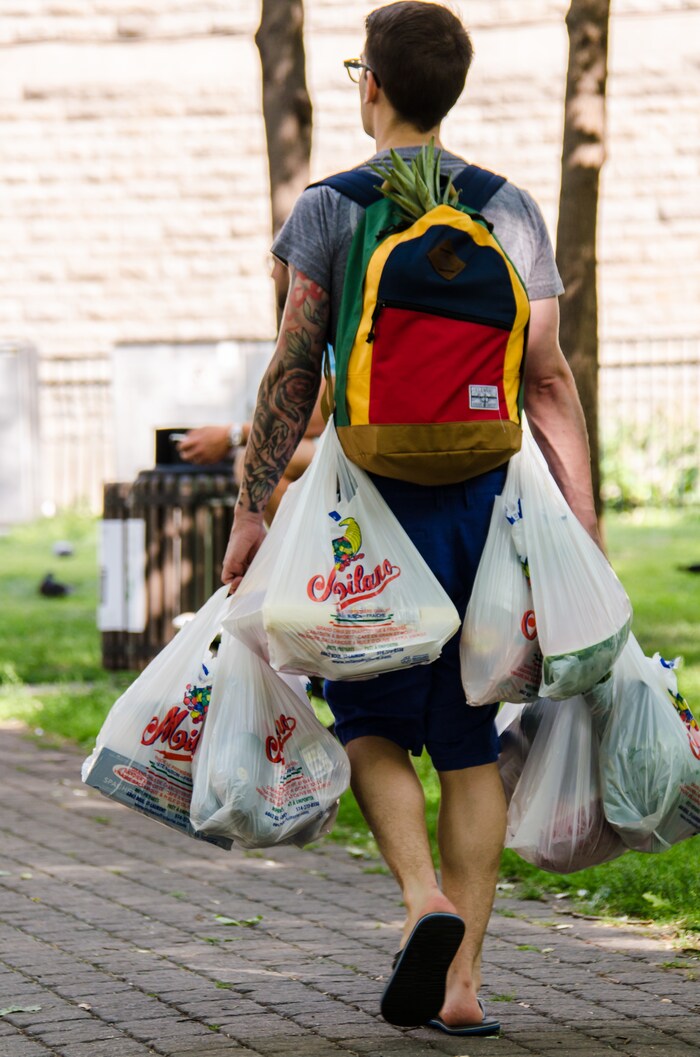 Un homme transporte au moins sept sacs d'emplettes en plastique