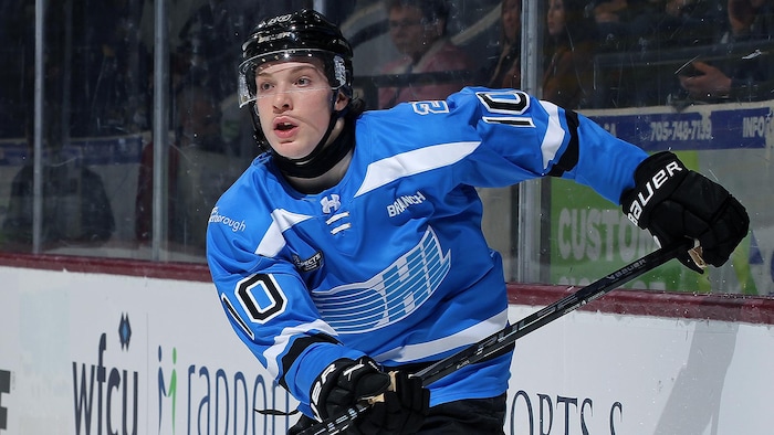 Un joueur de hockey en mouvement le long de la bande.