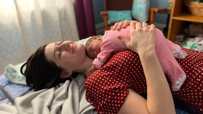 Jessica Ruano se repose sur son lit avec Joy couchée sur elle. 