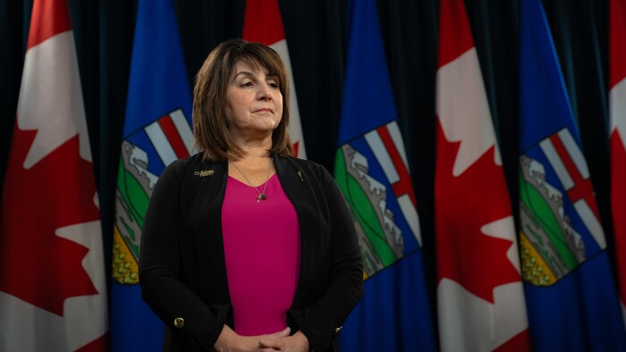 Adriana LaGrange devant des drapeaux canadiens et albertains.