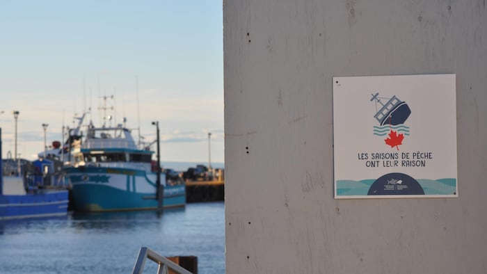 Une affiche qui indique « Les saisons de pêche ont leur raison » sur un quai.